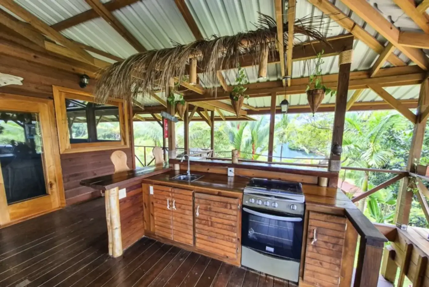 Main kitchen with thatched palm overhang, granite counters, and a view to the water