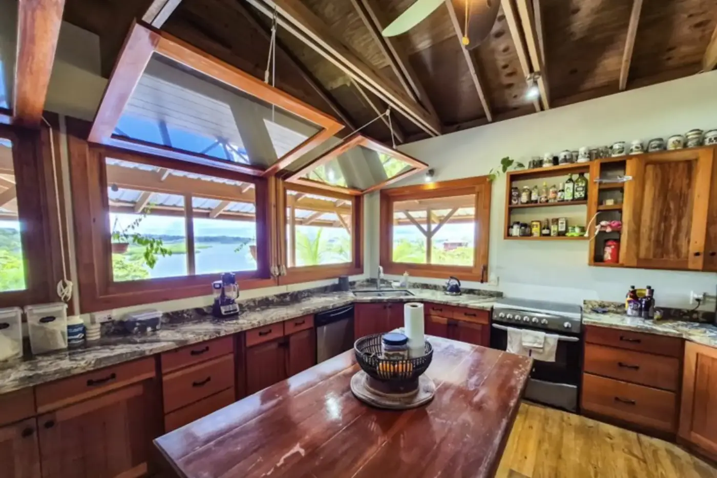 A bright kitchen with granite counters and big windows opening to the water